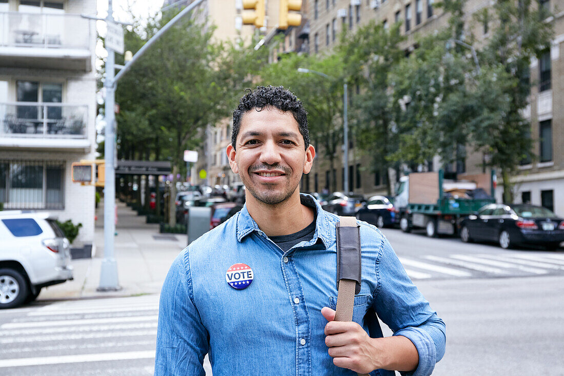 USA, New York, New York City, Portrait of smiling man with vote badge in city