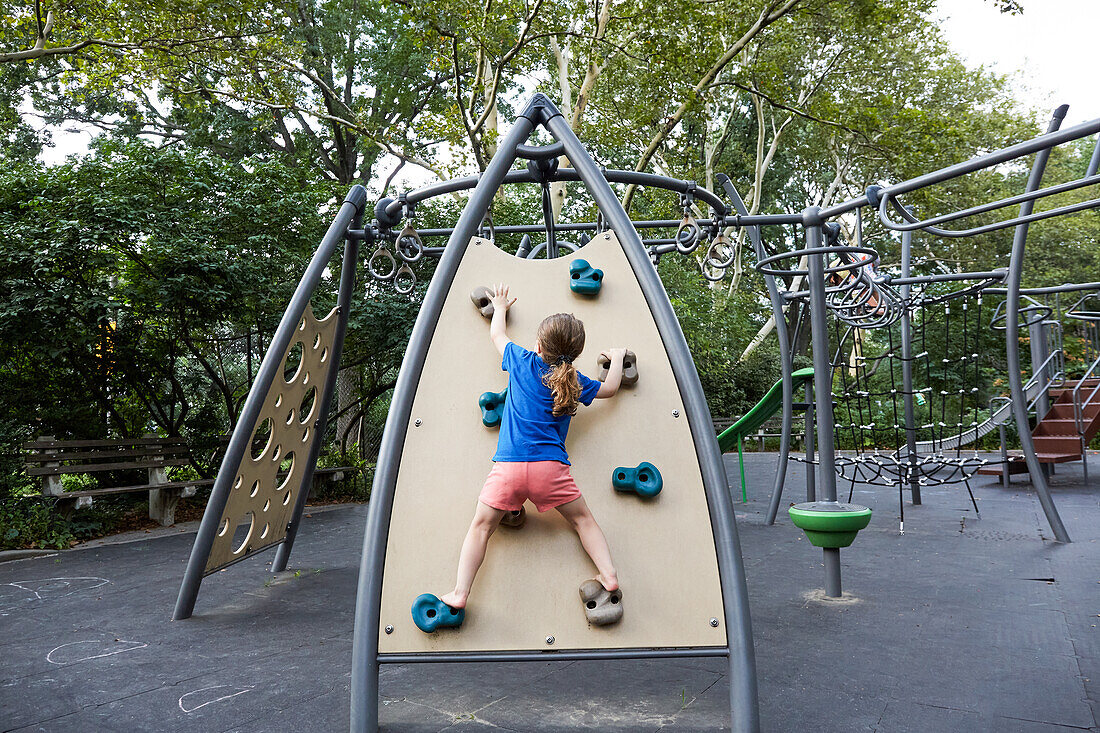 USA, New York, New York, Rear view of girl (2-3) on climbing wall at playground