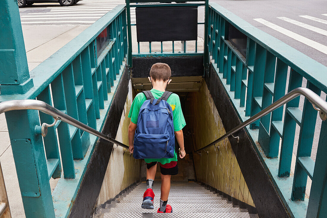 USA, New York, New York City, Rear view of boy (8-9) with backpack entering subway on way to school