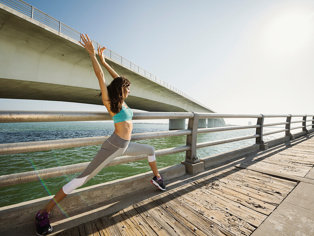 Frau dehnt sich auf einer Brücke an einem sonnigen Tag