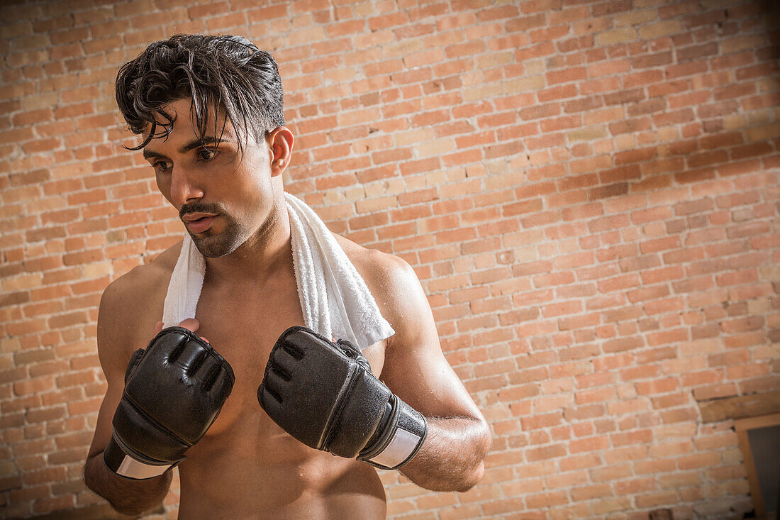 Shirtless man with boxing gloves and towel in gym
