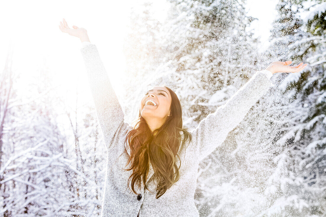 Happy woman with arms raised in snow covered forest