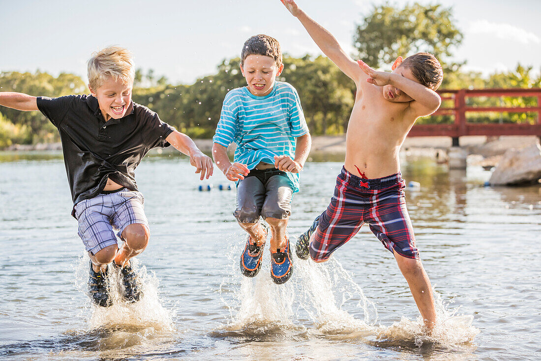 Boys (8-9) jumping in lake