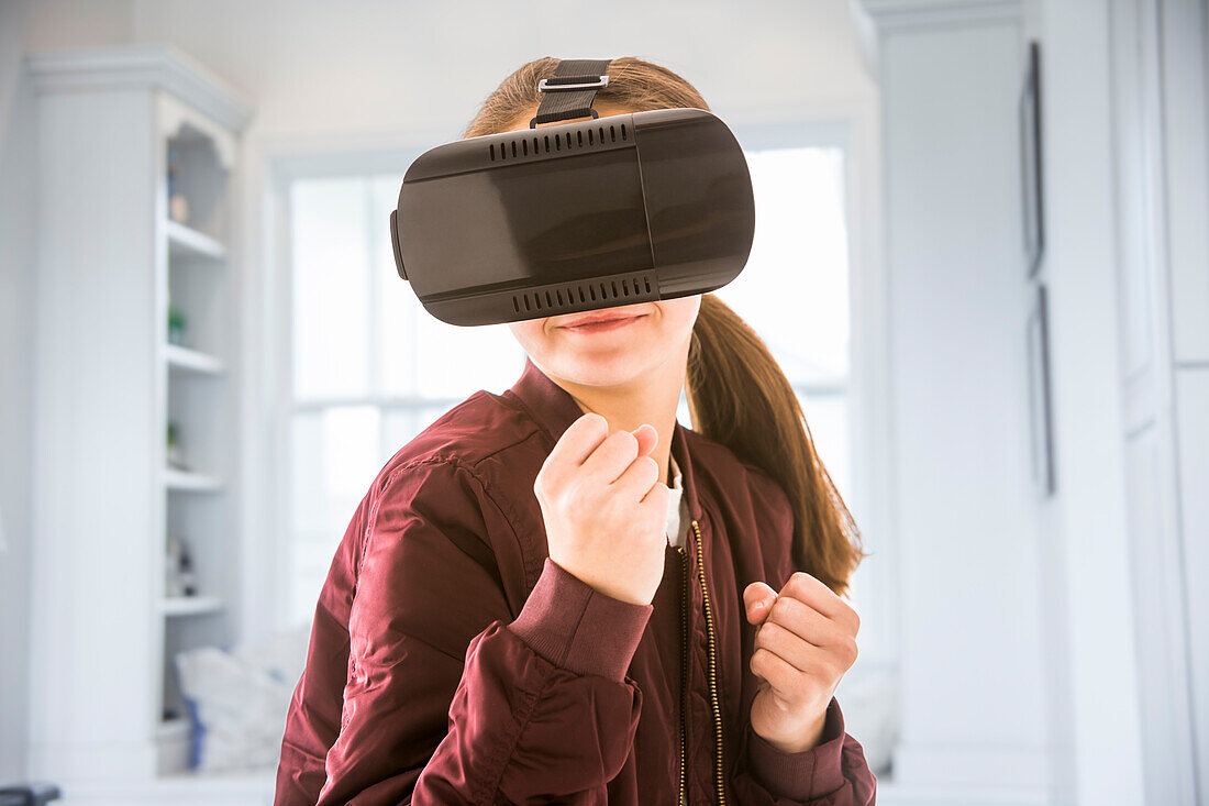 Girl (12-13) with VR goggles at home