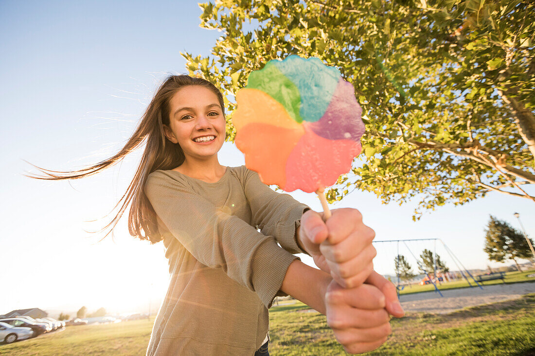 Portrait of girl (12-13) with colorful lollipop in park