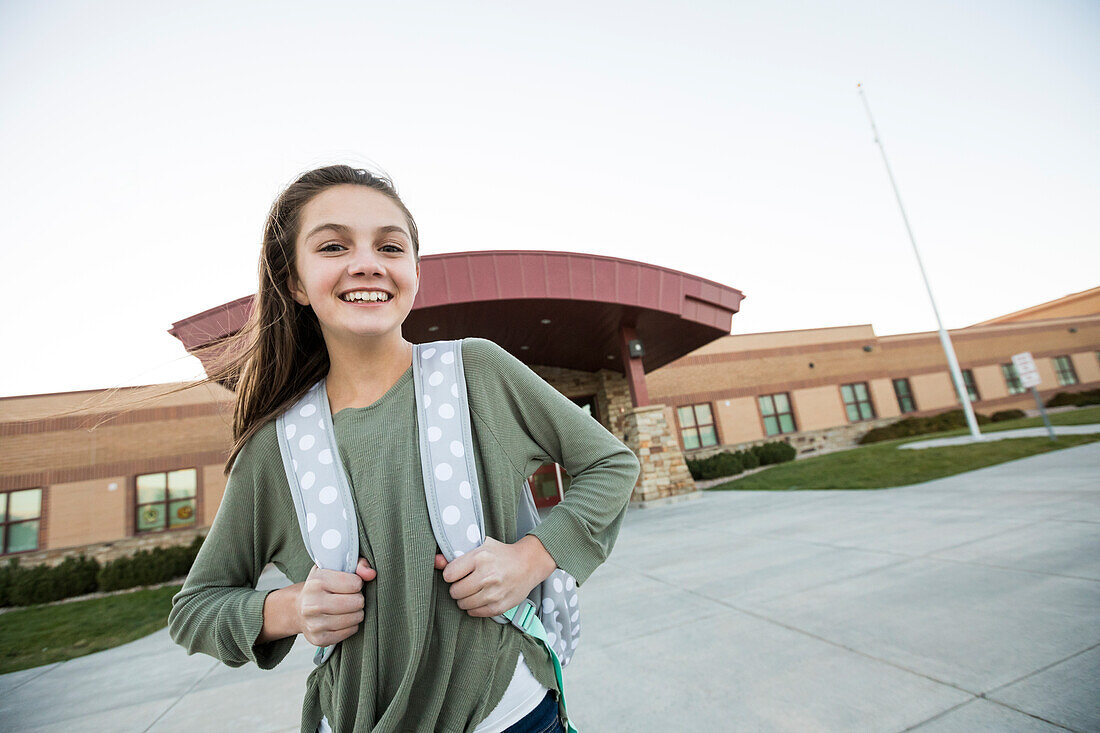 Vereinigte Staaten, Utah, Lehi, Porträt eines lächelnden Mädchens (12-13) vor einem Schulgebäude