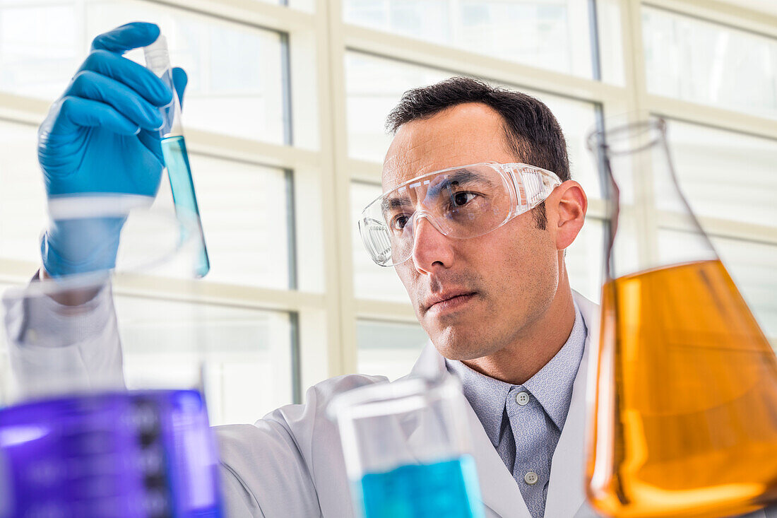 Wissenschaftlerin betrachtet blaue Flüssigkeit im Labor