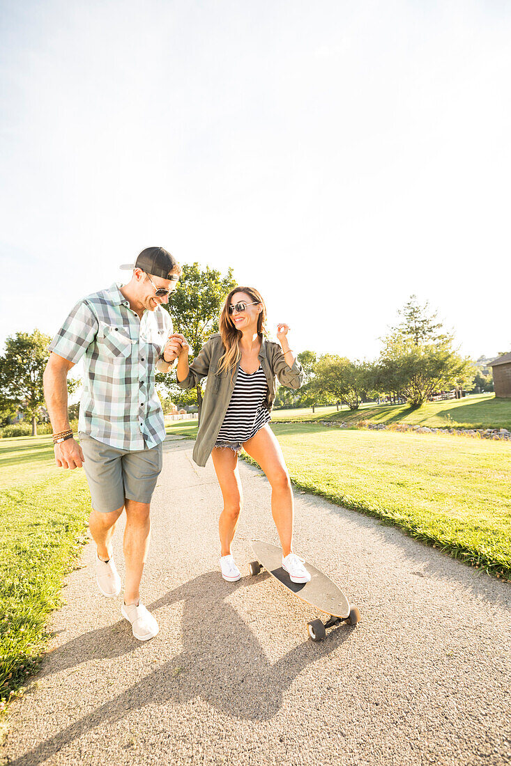 Smiling couple with skateboard in park