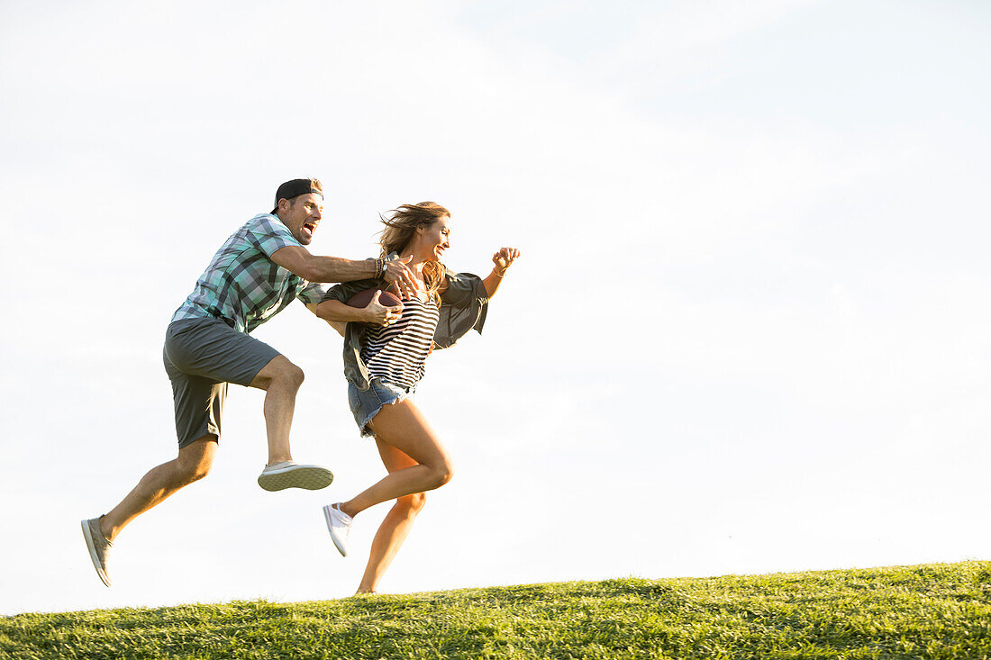 Frau und Mann rennen auf einem Hügel im Park 