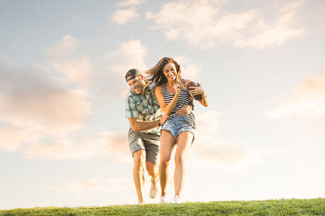 Smiling couple running on lawn with ball