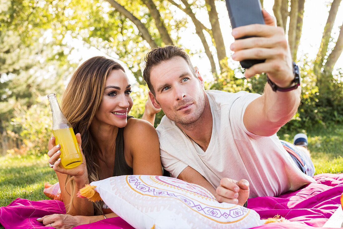 Mann fotografiert mit Smartphone bei Picknick im Park