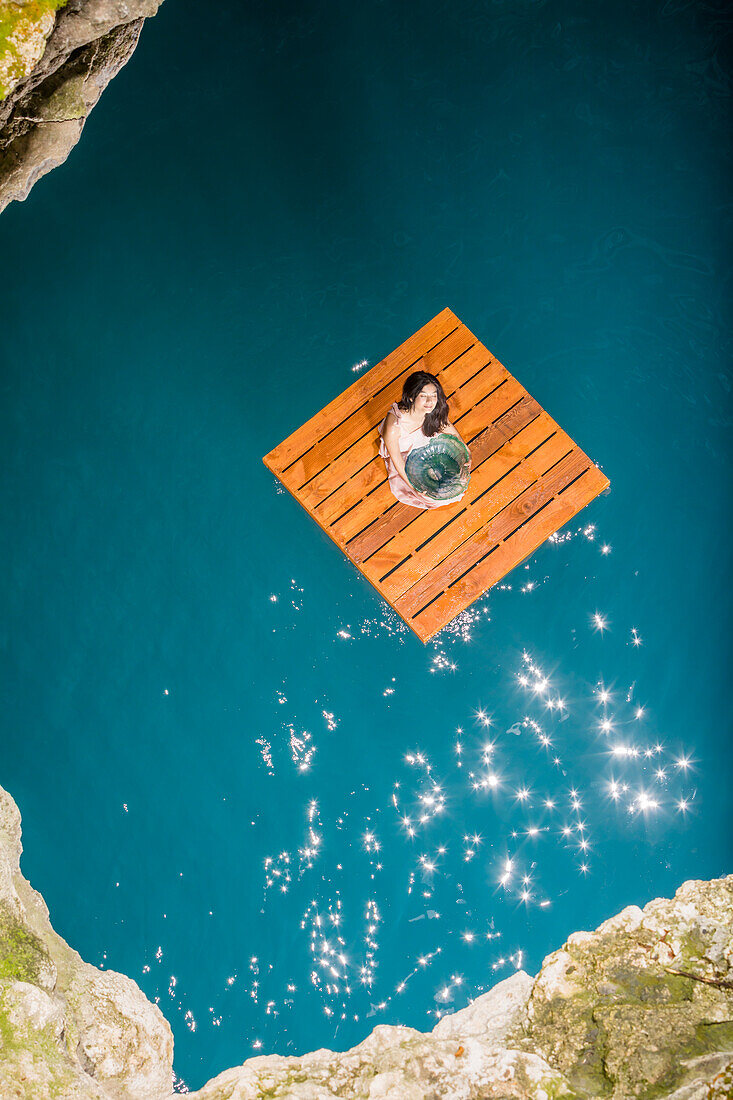 Luftaufnahme einer Frau auf einem Holzfloß sitzend