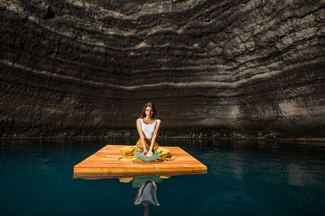 Frau sitzend auf Holzfloß in Cenote