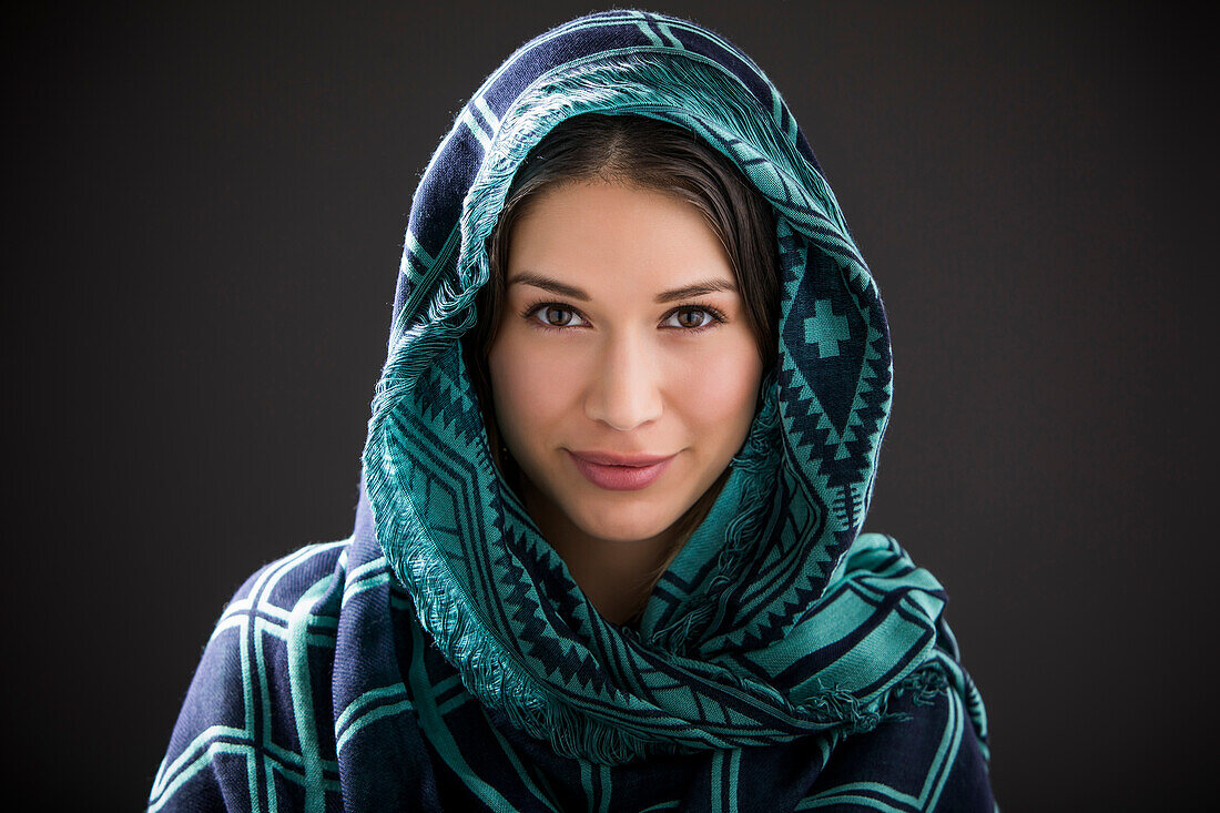 Studio-Porträt einer lächelnden Frau mit Schal auf dem Kopf