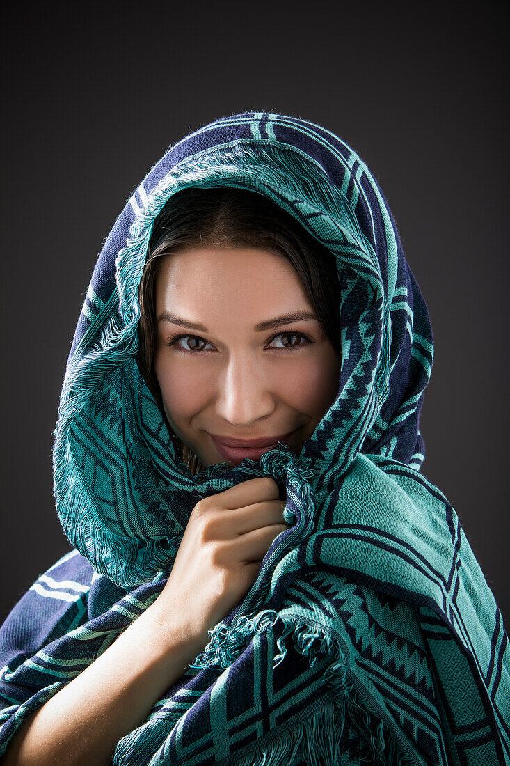 Studioporträt einer lächelnden Frau mit Schal auf dem Kopf