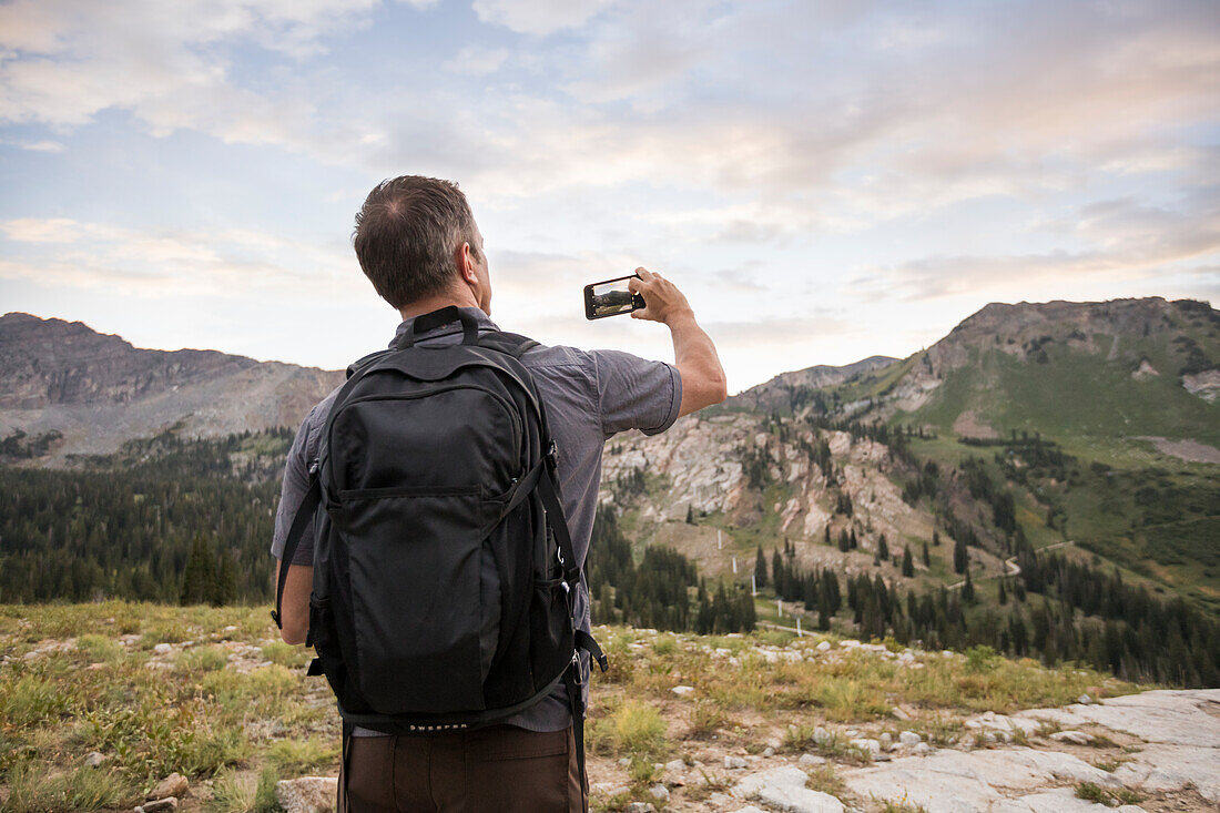 Vereinigte Staaten, Utah, Alpin, Männlicher Wanderer fotografiert Berge mit Smartphone