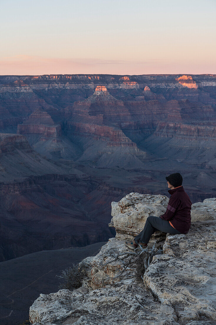 United States, Arizona, Grand Canyon National Park, South Rim, Senior female hiker sitting at edge of Grand Canyon and looking at view 