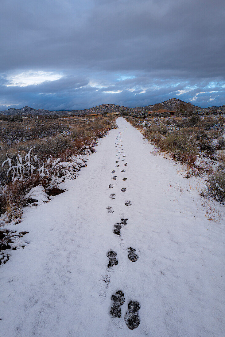 Vereinigte Staaten, New Mexico, Santa Fe, Fußabdrücke im Schnee unter bewölktem Himmel 