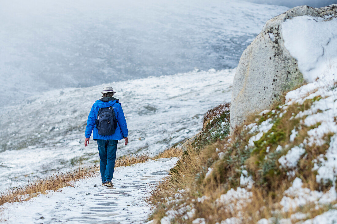 Australien, New South Wales, Frau wandert auf verschneitem Weg am Charlotte Pass im Kosciuszko-Nationalpark