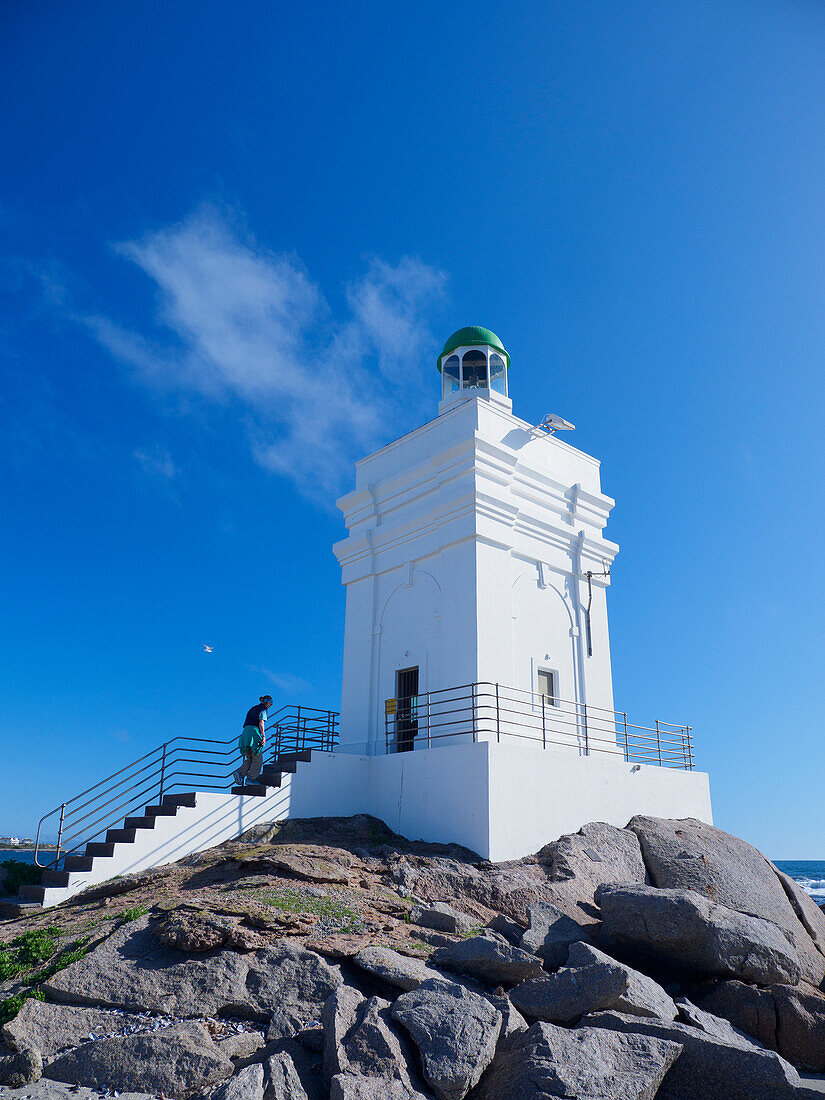 Südafrika, Westkap, St. Helena, Frau besteigt weißen Leuchtturm an der Meeresküste
