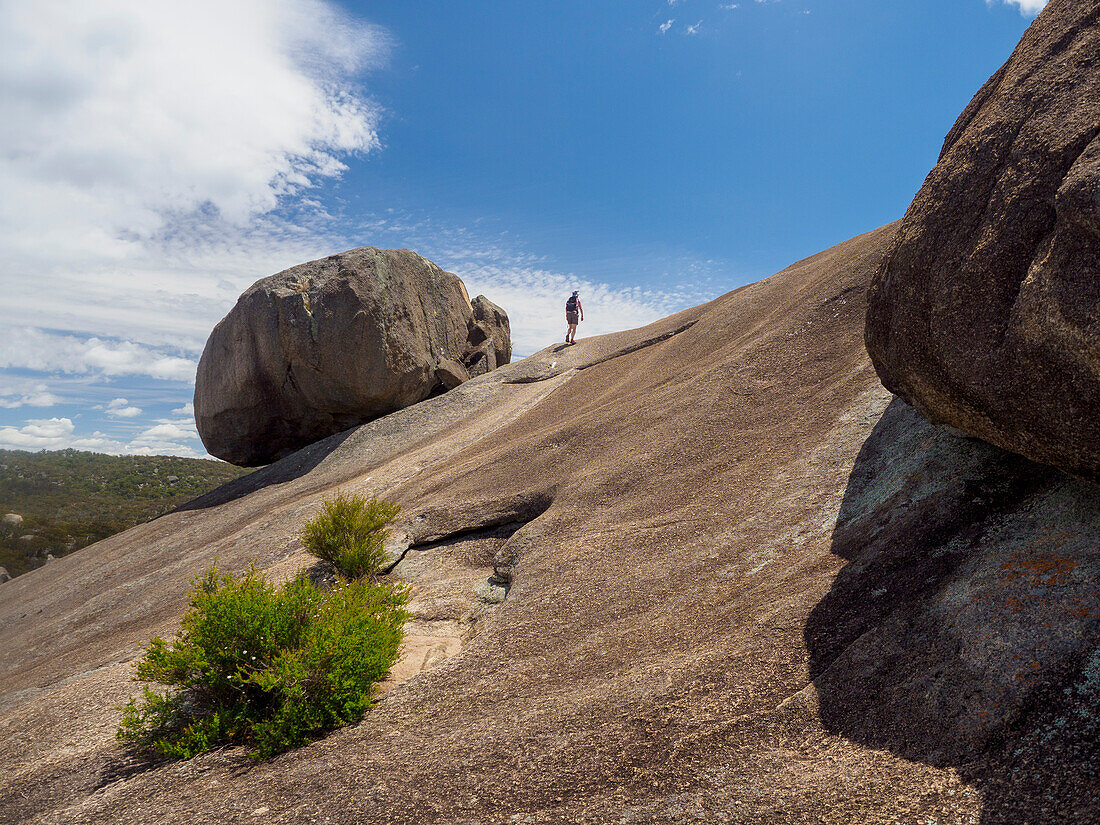 Australien, Queensland, Girraween-Nationalpark, Frau wandert auf einer Felsformation