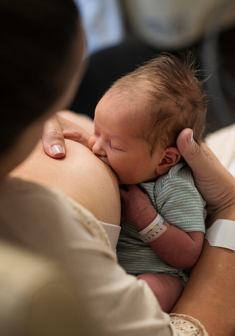 Mother breastfeeding newborn baby girl (0-1 months)