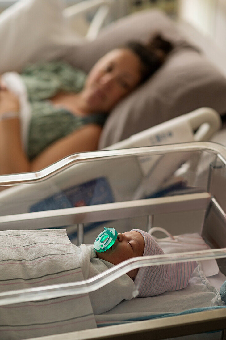 Mutter liegend mit neugeborenem Mädchen (0-1 Monate) im Krankenhaus