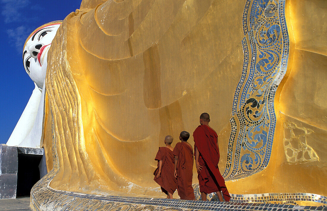 Myanmar, Monyma, Division Mandalay, Mönchsanwärter beten unter der riesigen Statue eines liegenden Buddhas im Lay Kyune Sakkyar-Tempel