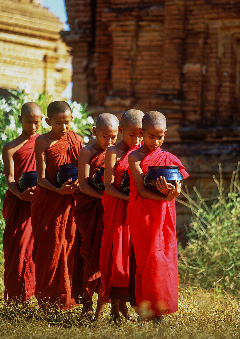 Myanmar, Bagan, Division Mandalay, Buddhistische Mönche halten Schalen während der morgendlichen Almosengabe