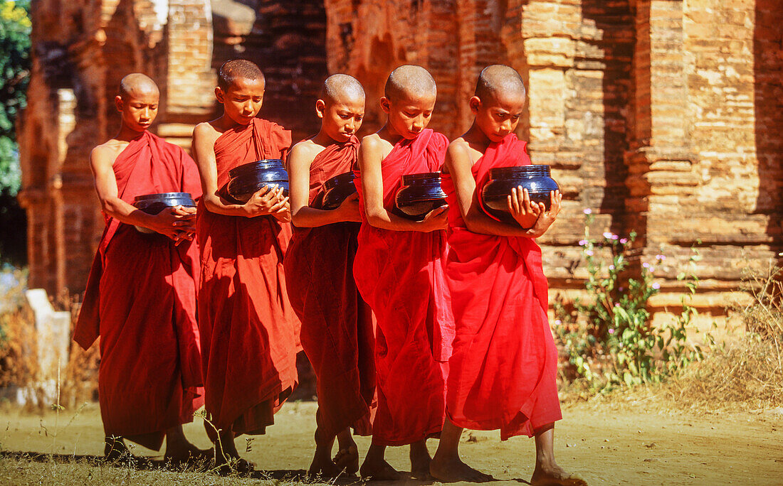 Myanmar, Bagan, Division Mandalay, buddhistische Mönche halten Schalen während der morgendlichen Almosengabe