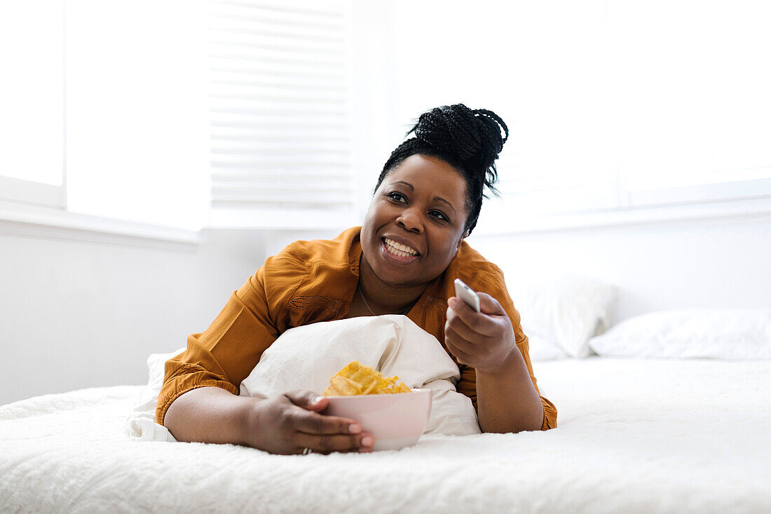 Frau isst Kartoffelchips im Bett