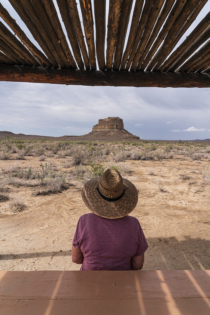 USA, New Mexico, Chaco Canyon National Historic Park, Rückansicht einer Frau mit Strohhut mit Blick auf die Fajada Butte im Chaco Canyon im Chaco Culture National Historical Park