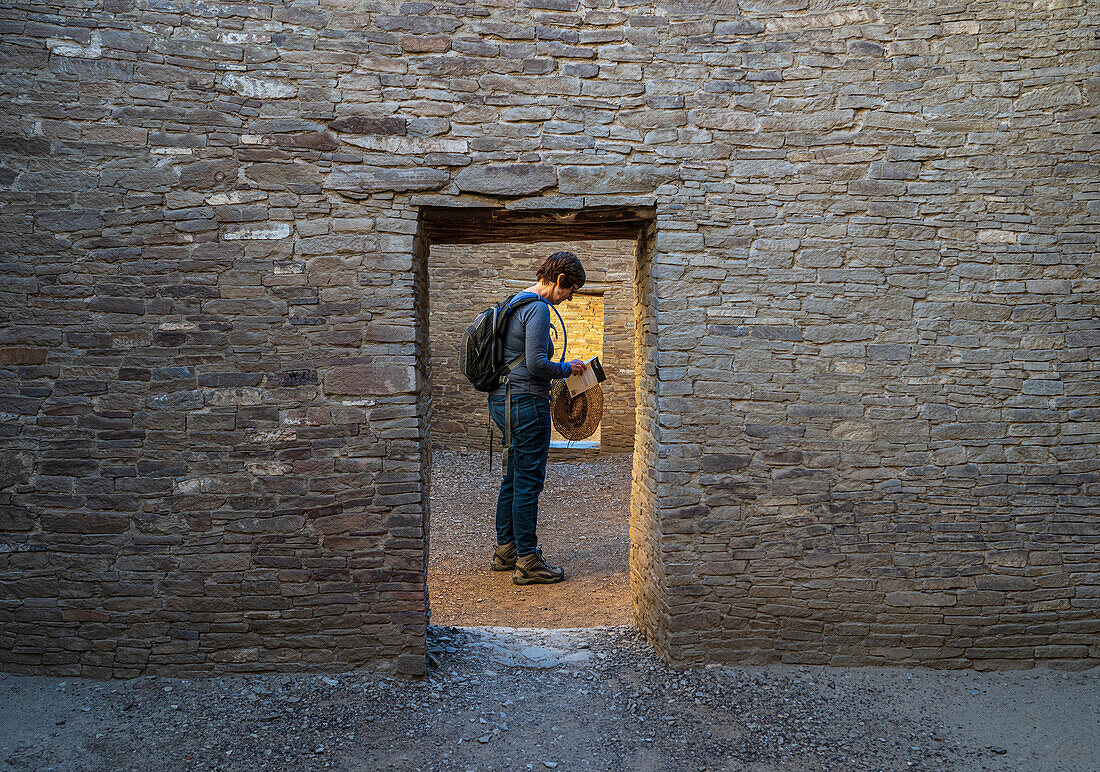 USA, New Mexico, Chaco Canyon National Historic Park, Female tourist reading guidebook at Pueblo Bonito