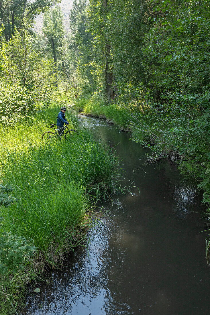 USA, Idaho, Bellevue, Senior man on bicycle looking at stream