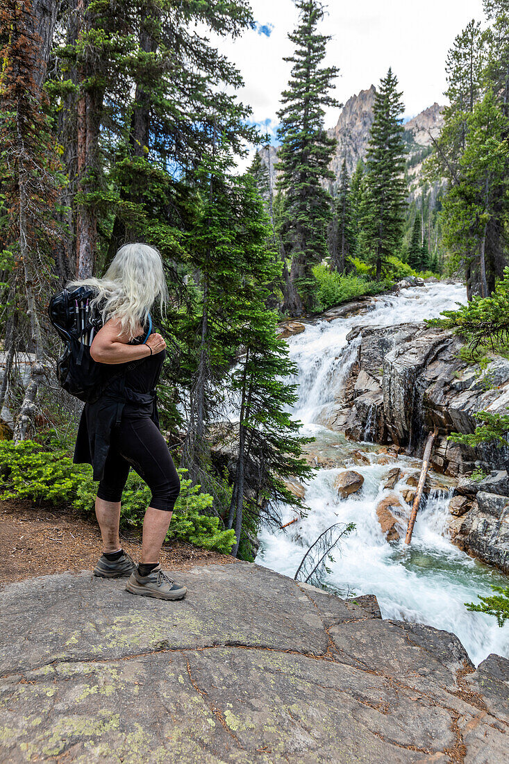 USA, Idaho, Stanley, Ältere Wanderin mit Blick auf einen Wasserfall