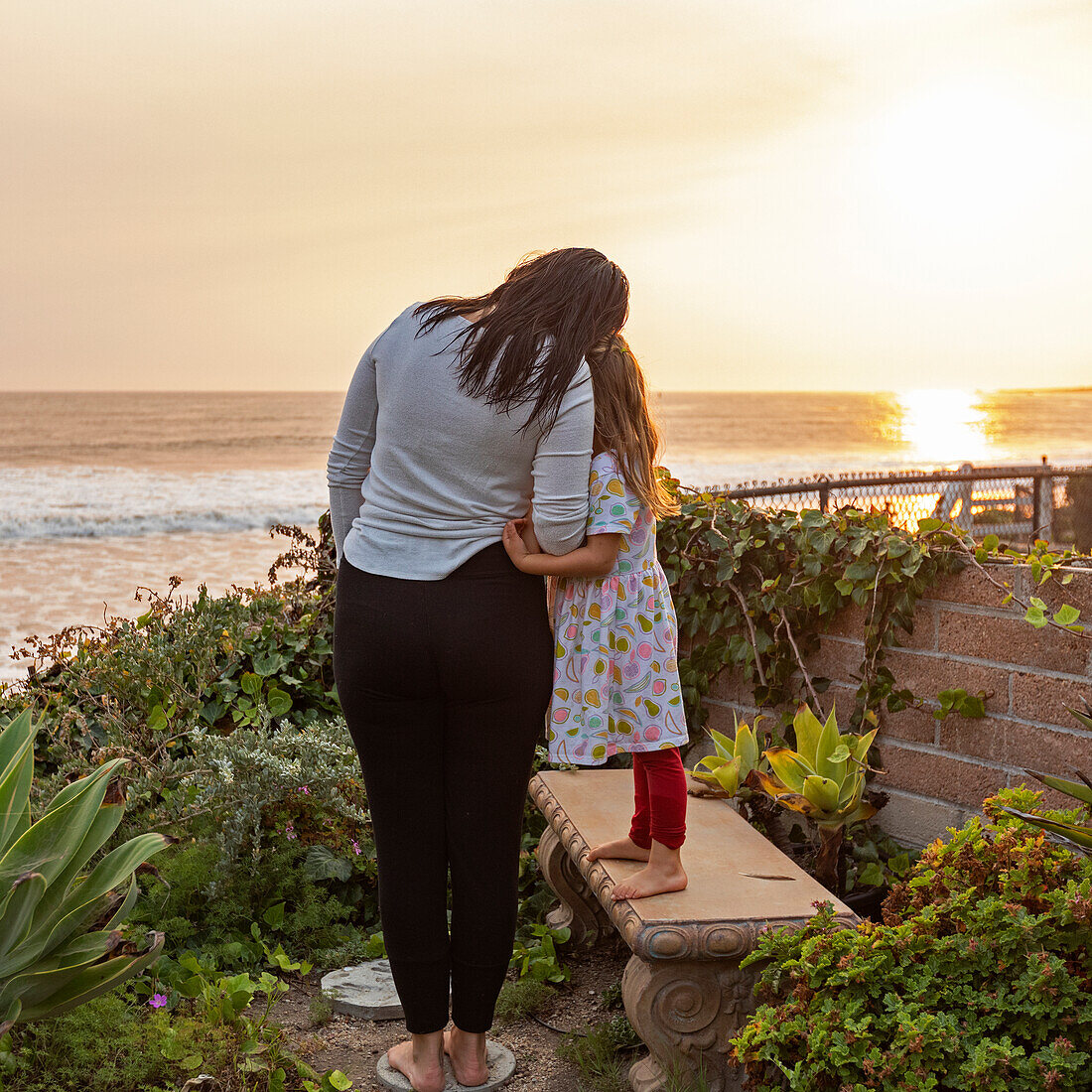 USA, California, Cayucos, Mother and daughter (4-5) on bluff above beach at sunset