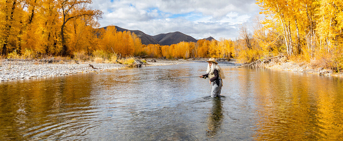 USA, Idaho, Bellevue, Ältere Frau beim Fliegenfischen im Big Wood River im Herbst
