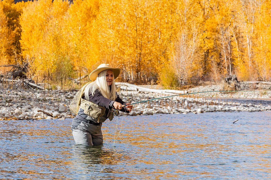 USA, Idaho, Bellevue, Ältere Frau beim Fliegenfischen im Big Wood River im Herbst