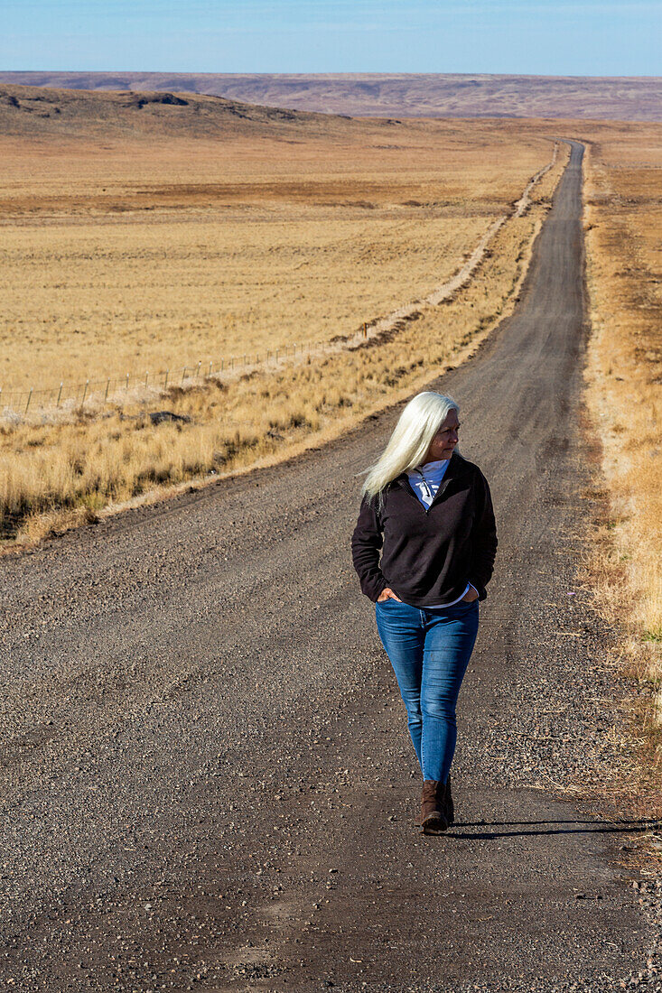 USA, Nevada, Winnemucca, Senior woman walking down desert road
