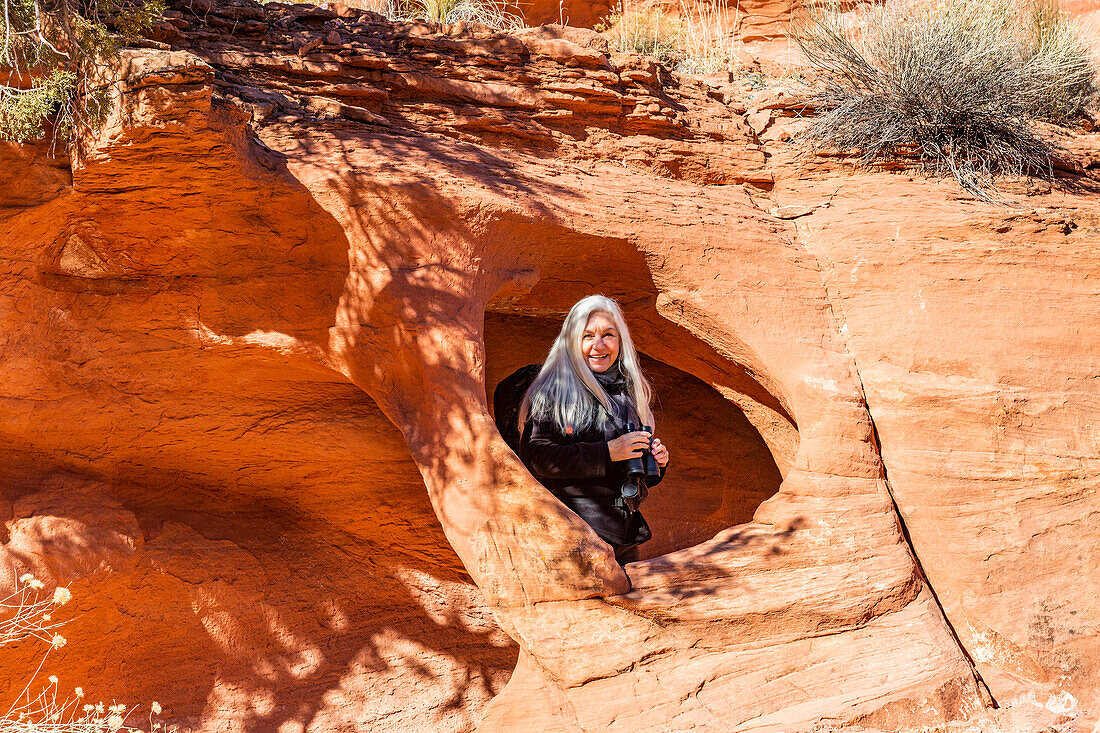 Vereinigte Staaten, Utah, Escalante, Älterer Wanderer steht in einer Felsöffnung in einem Sandsteinfelsen