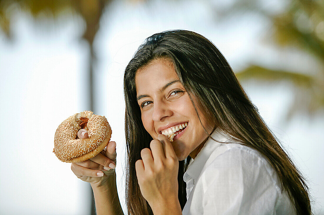 Porträt einer lächelnden Frau, die einen Donut isst