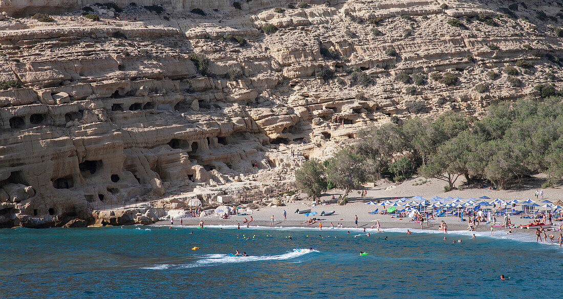 Griechenland, Kreta, Matala, Touristen liegen am Strand und baden im Meer