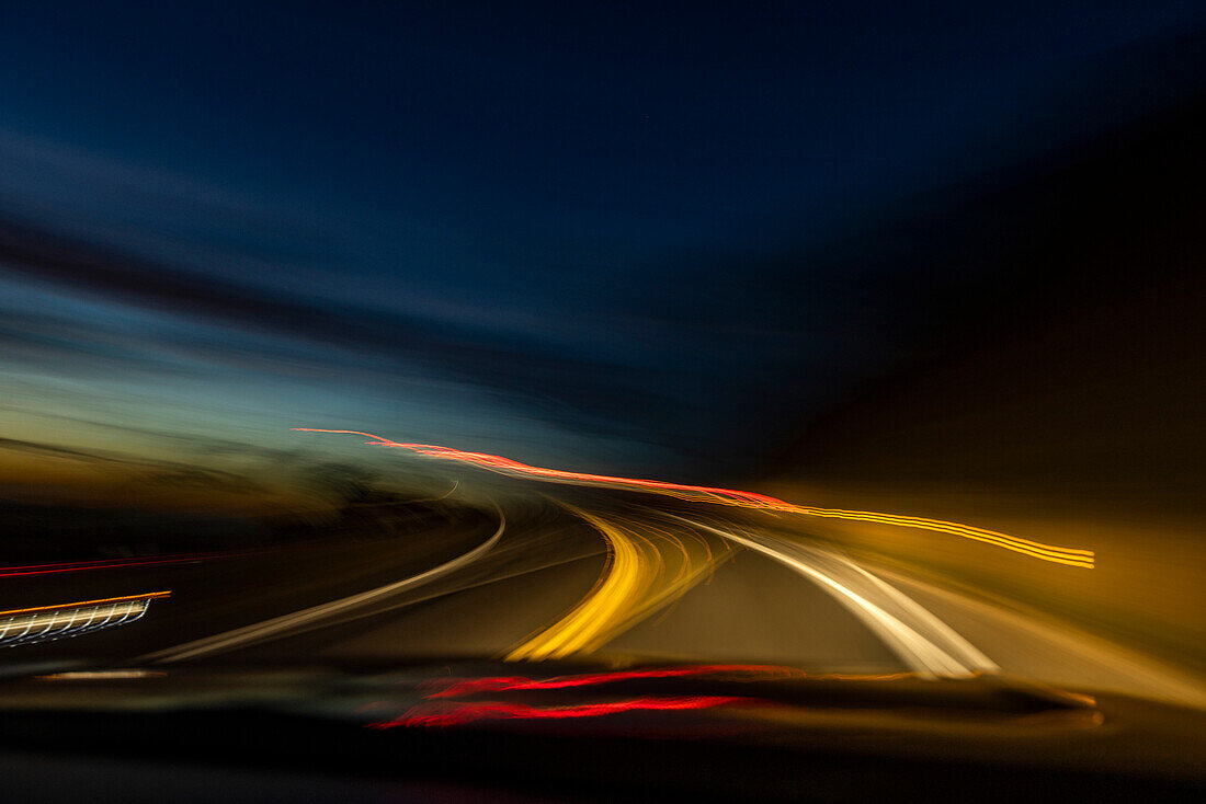 Unscharfes Bild von Lichtern auf dem Highway in der Abenddämmerung