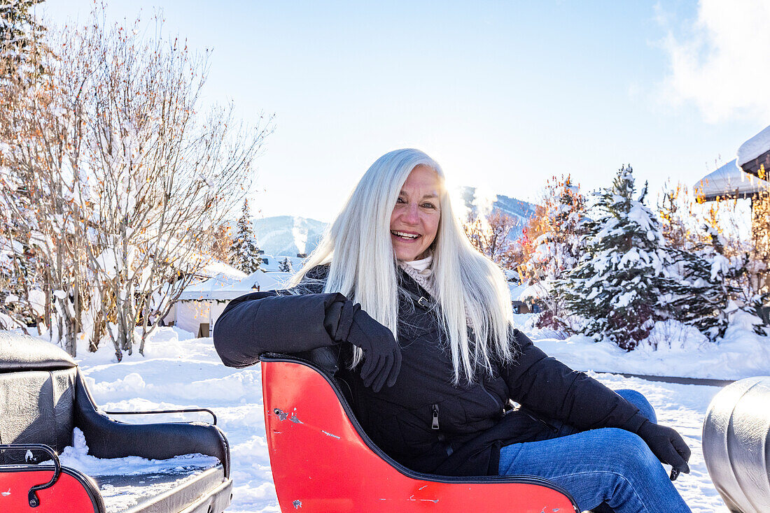 United States, Idaho, Sun Valley, Portrait of senior woman sitting in snowy sleigh