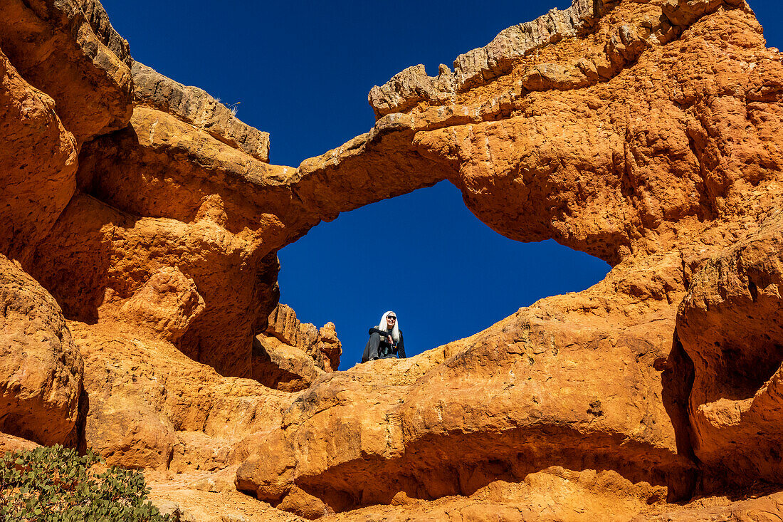 Vereinigte Staaten, Utah, Escalante, Älterer Wanderer sitzt auf einem Sandsteinvorsprung