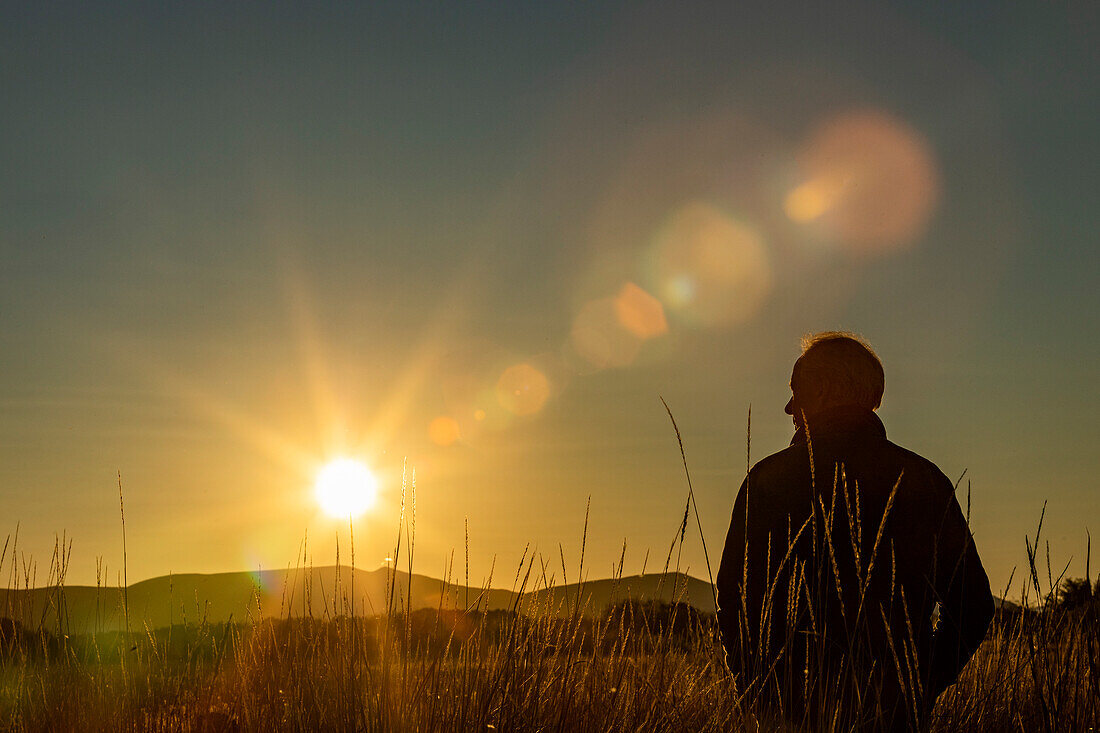 Silhouette eines Mannes auf einem Feld bei Sonnenuntergang 