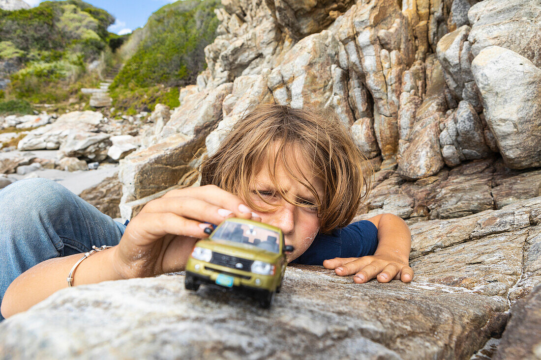 Junge (8-9) spielt im Freien mit Spielzeugautos