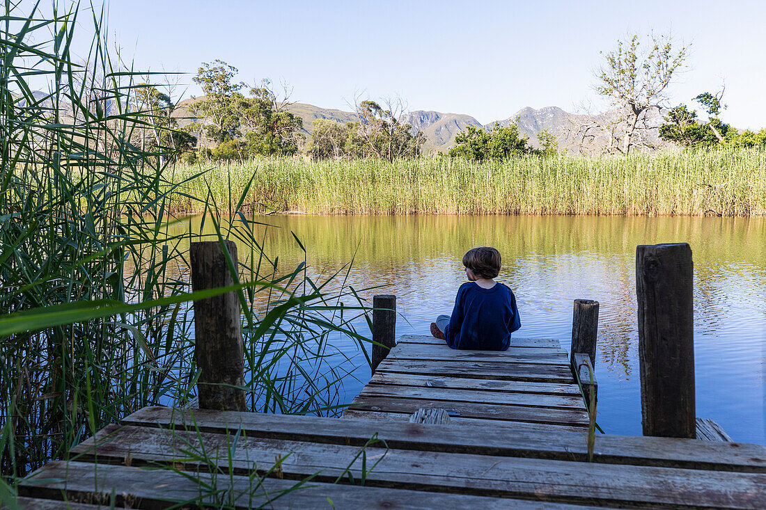Südafrika, Stanford, Junge (8-9) sitzt auf Holzsteg