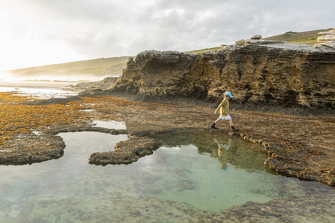 South Africa, Western Cape, Boy (8-9) exploring tidal pools in Lekkerwater Nature Reserve