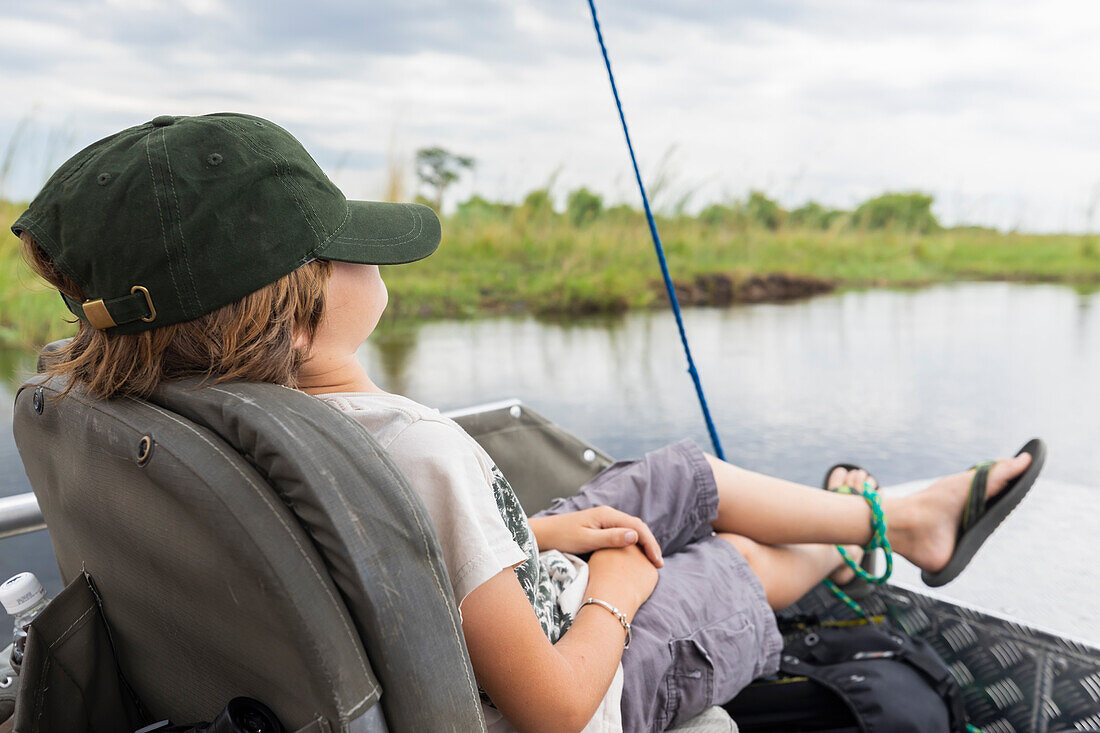 Africa, Zambia, Boy (8-9) in boat on Zambezi River near Tongabezi River Lodge